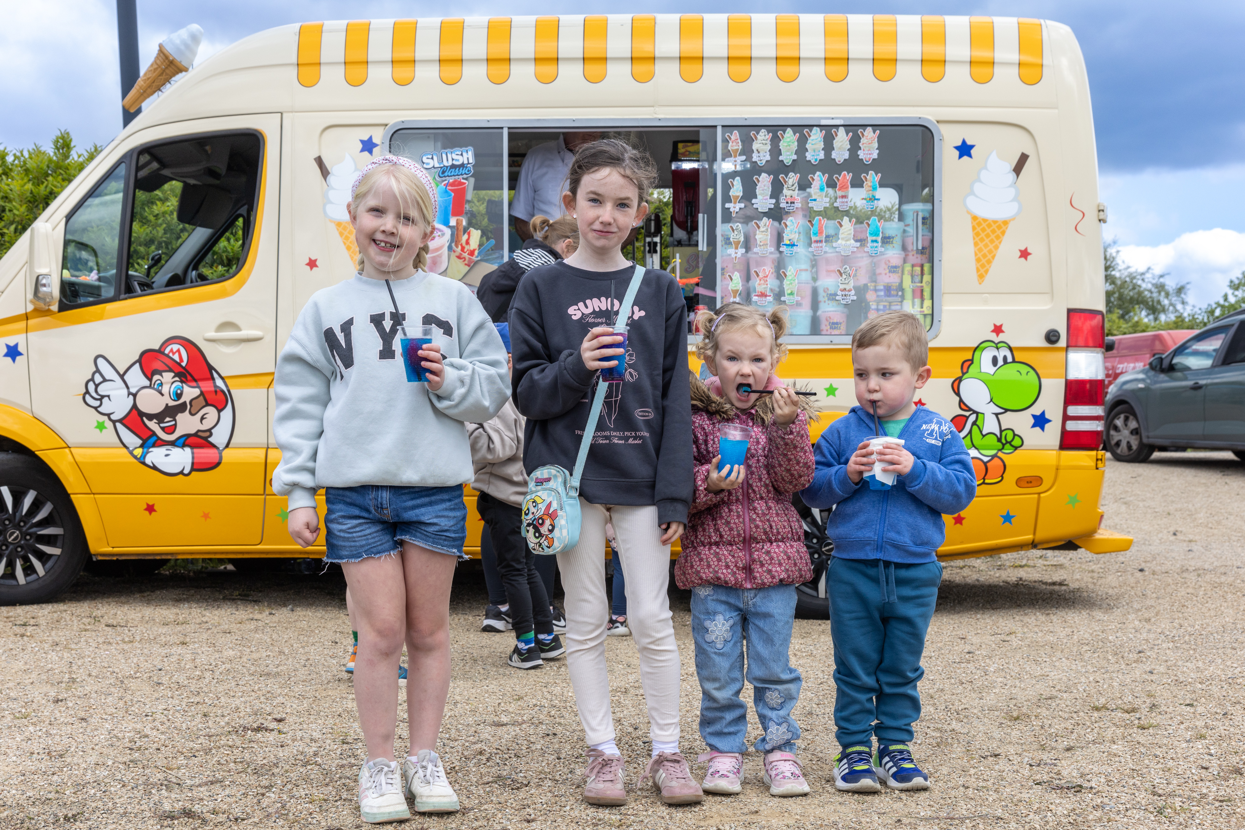 Children with slushies in front of an ice-cream van.